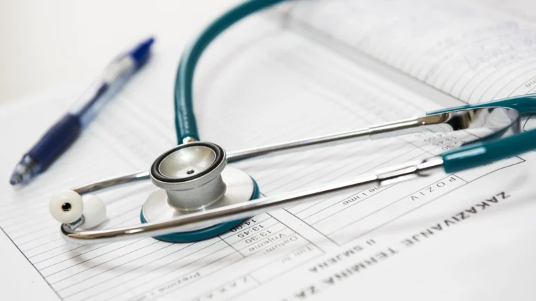 Close-up of a stethoscope resting on a medical chart with handwritten notes, alongside a pen, symbolizing healthcare documentation and patient care