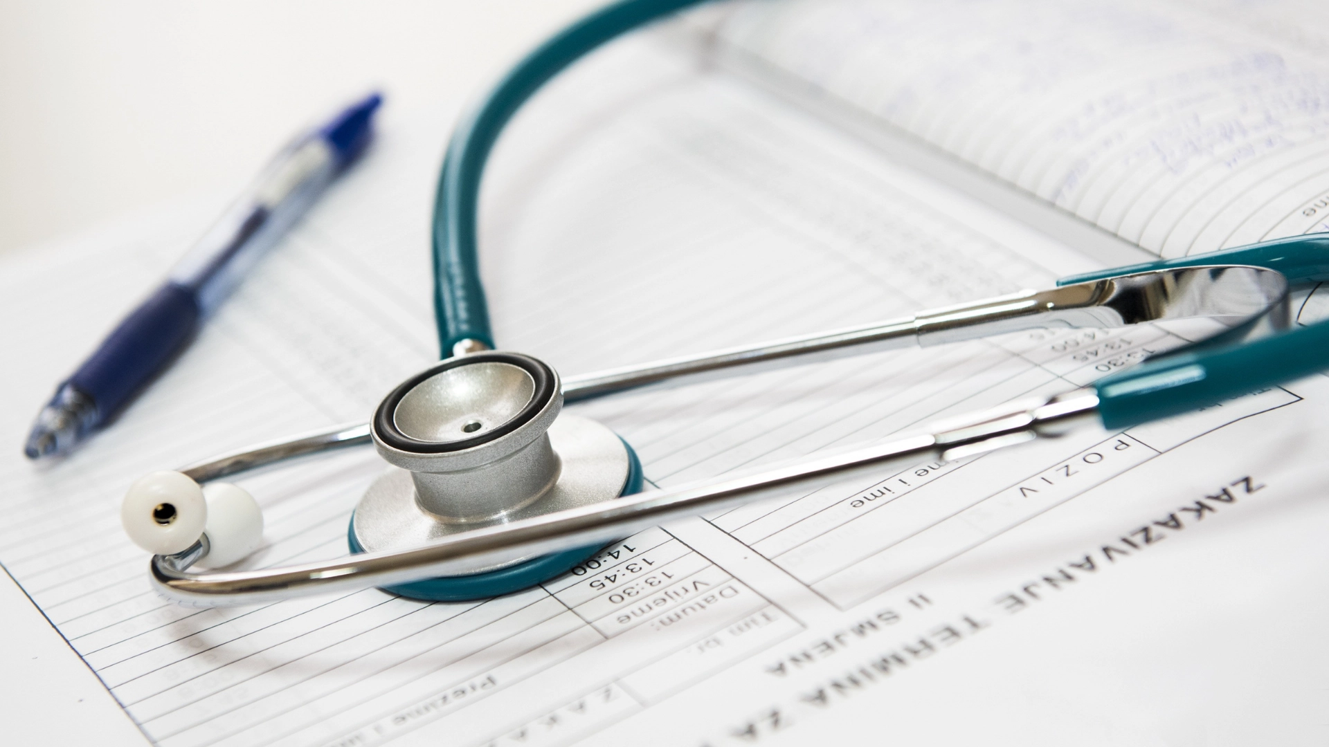 Close-up of a stethoscope resting on a medical chart with handwritten notes, alongside a pen, symbolizing healthcare documentation and patient care