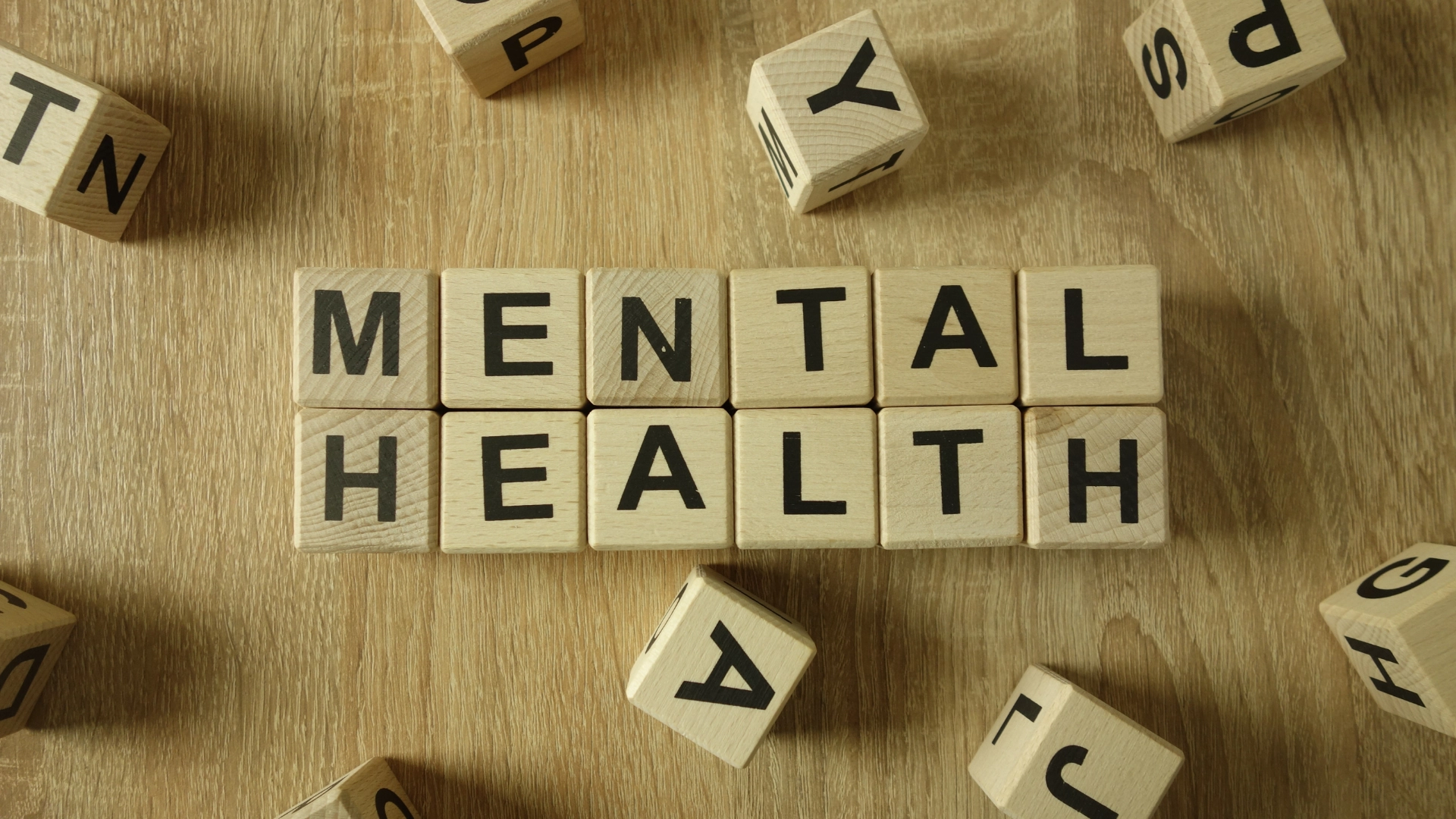 Wooden letter blocks spelling out “Mental Health” on a wooden table, symbolizing awareness and discussion around mental health and wellness