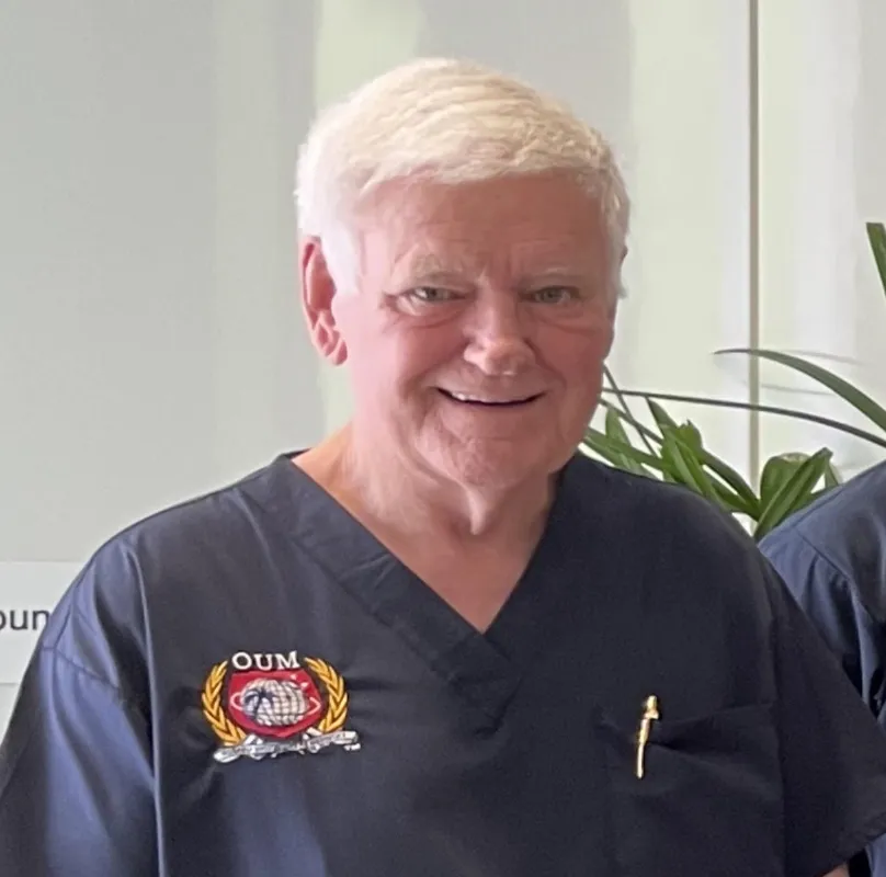 White haired smiling doctor in nave scrubs