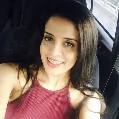 Photo of smiling young female with long brown hair, brown eyes, and a burgundy blouse.