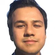 A headshot portrait of a man with short, dark hair. He has brown-colored eyes and a slight smile.